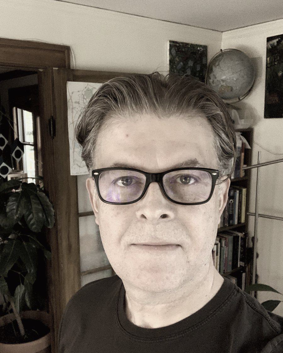 Siegfried Martens in the study, globe and bookshelves behind